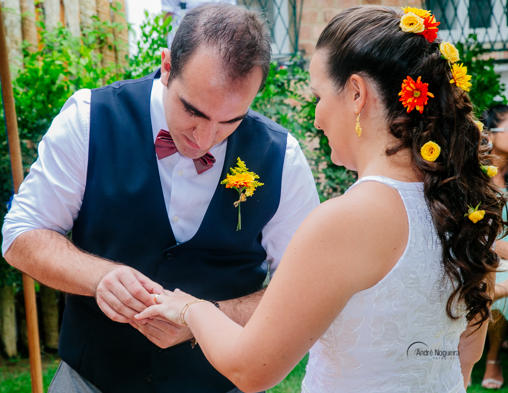 momento de troca de alianças e o noivo colocando o símbolo do amor entres que aliança, no dedo da noiva.