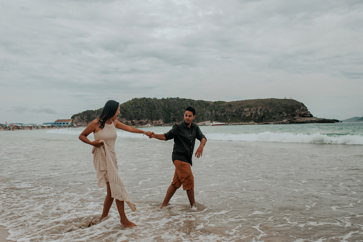 casal correndo de mãos dadas na praia das conchas durante o ensaio casal