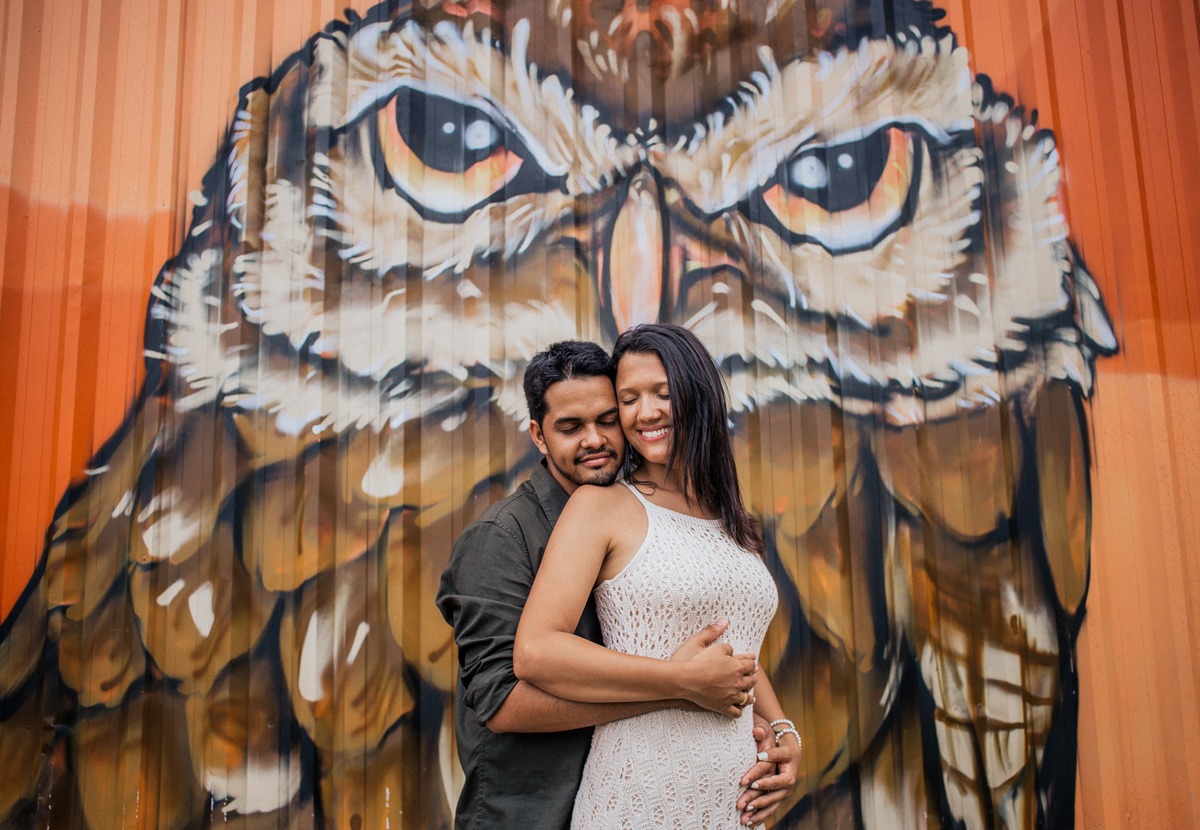 casal abraçado em frente a pintura da coruja na praia das conchas cabo frio