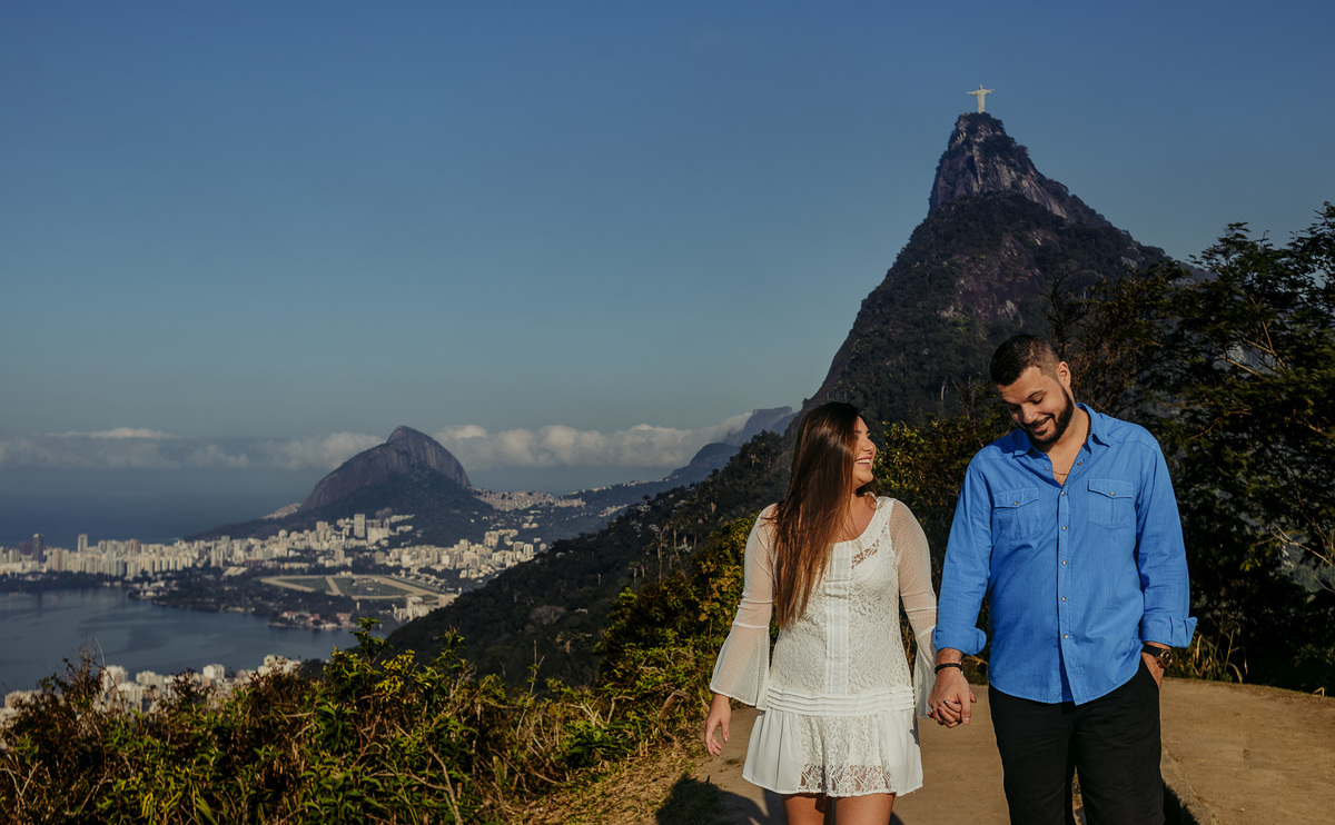 no mirante dona marta casal caminha de mãos dadas e sorrindo durante o ensaio pré casamento rj