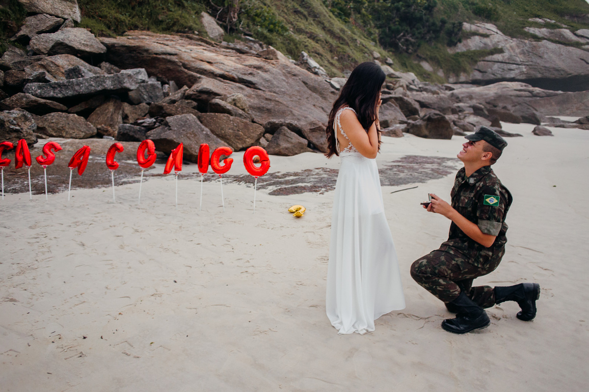 noivo ajoelhado pedindo a noiva em casamento nas areias da praia do forte de copacabana