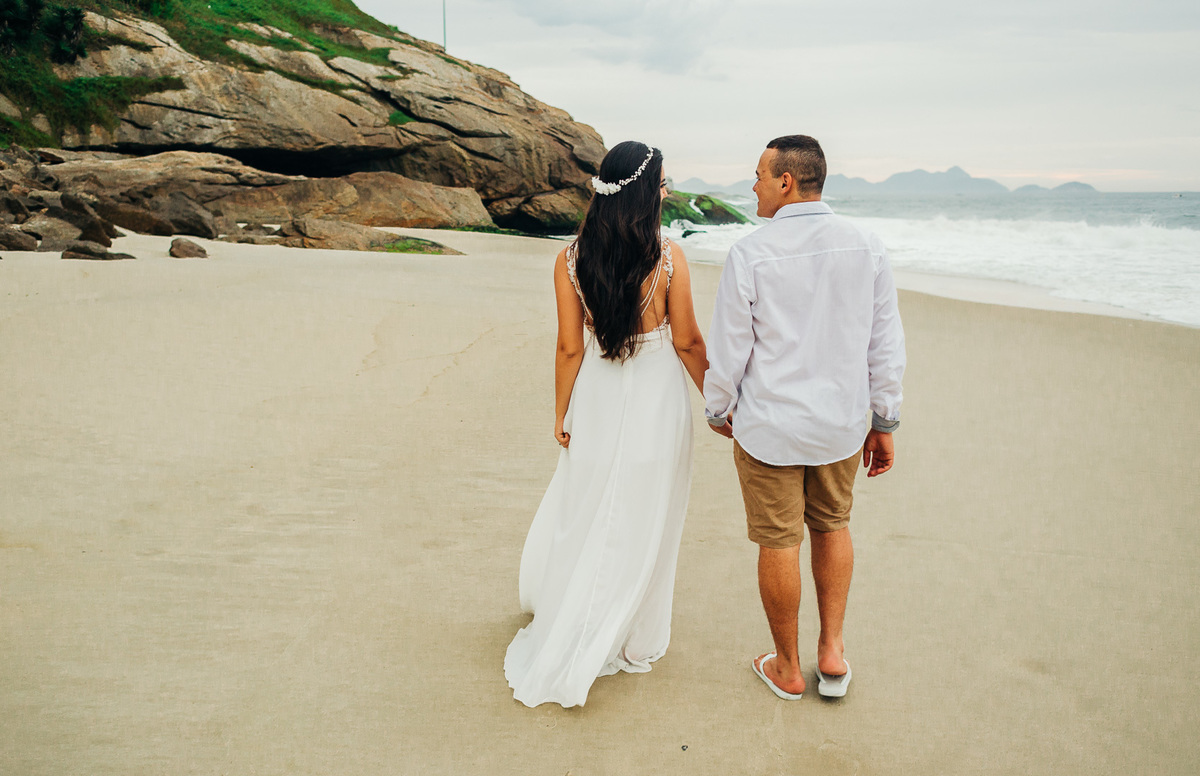 de mãos dadas o casal caminha pela areia da praia do forte de copacabana ensaio casal rj