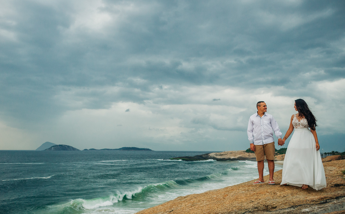 de mãos dadas casal se olha no forte de coapacabana durante o pre casamento fotografado por andre nogueira fotografia