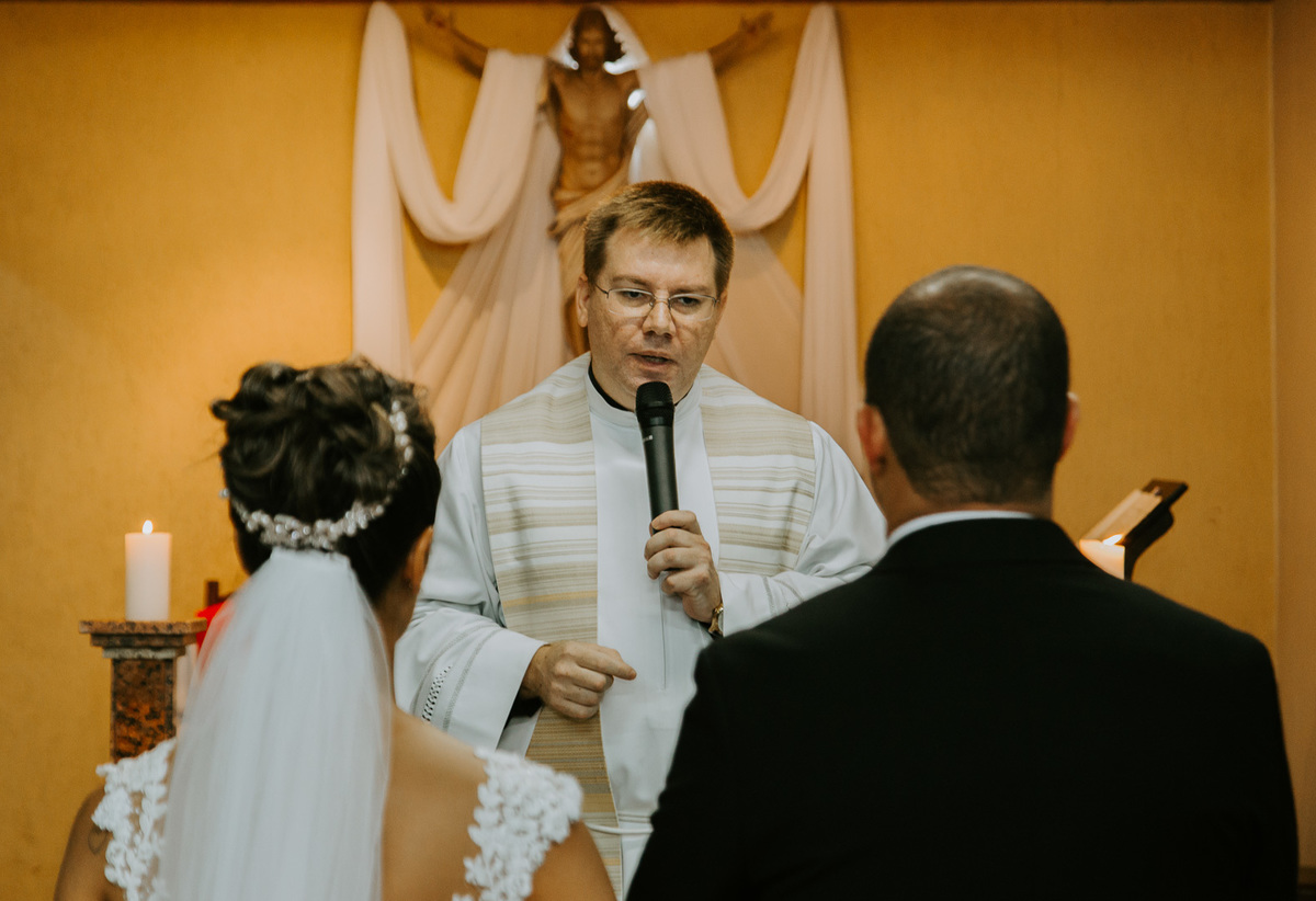 padre celebra a cerimonia de casamento para os noivos na igreja catolica vestido da noiva feito por morena andrade atelier