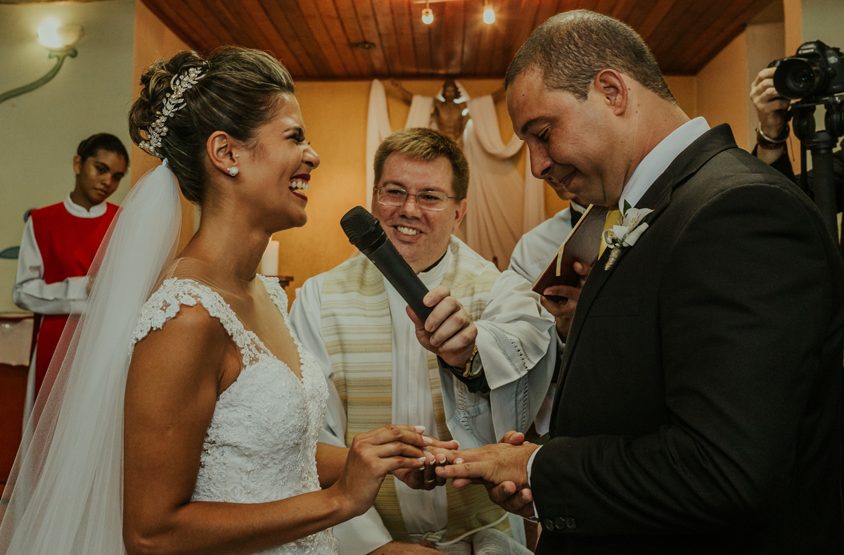 colocando a aliaça de casamento rj no dedo de seu noivo noiva sorri cerimonia religiosa rj