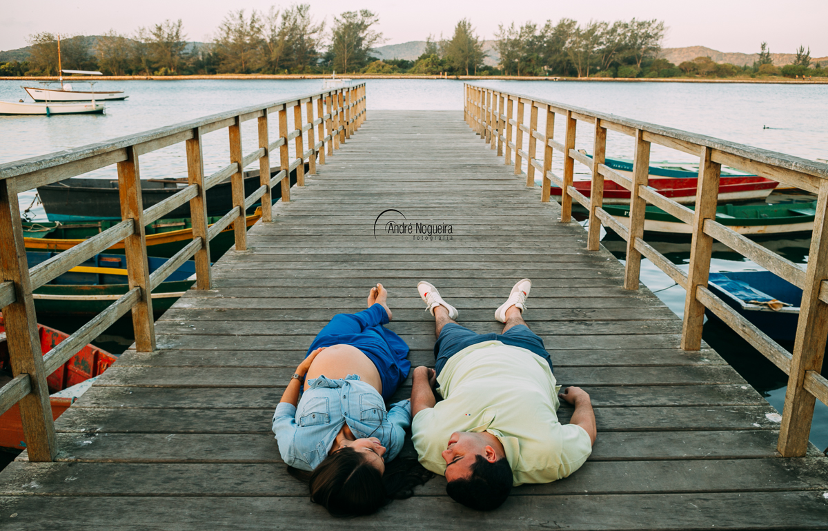 gestante rj, casal deitado na ponte da praia de cabo frio, ilha do japones, fotografo de gestante rj, andre nogueira fotografia