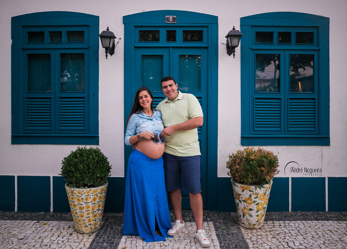 segurando o sapatinho na barriga em frente a uma porta azul
