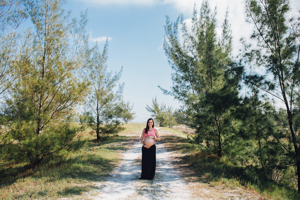 com as mãos na barriga dessa gestante linda, emoldurada por duas belas árvores
