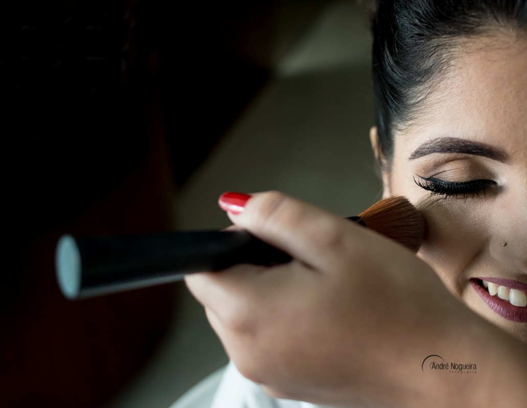 maquiadora passando o lápis de mauiagem no rosto da noiva