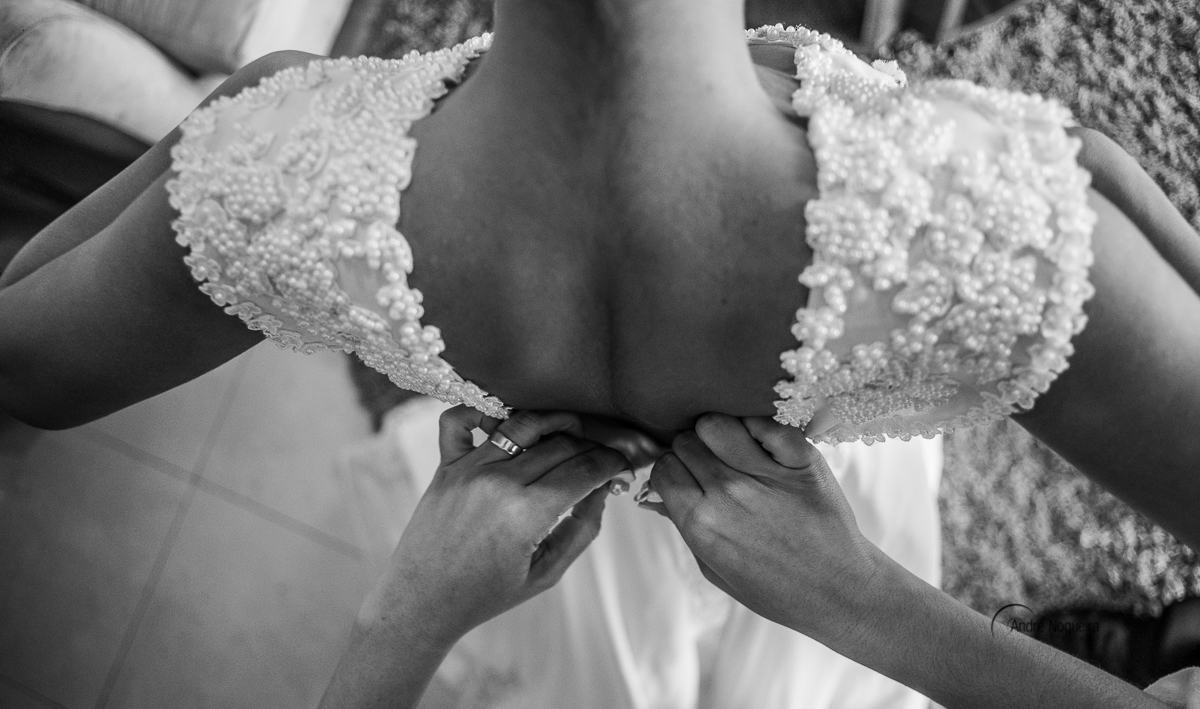 irmã da noiva abotoando o vestido de noiva dela