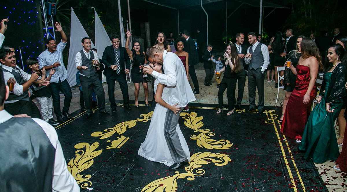 os noivos dançando juntinho na pista de dança e o noivo segurando o copo de cerveja na mão