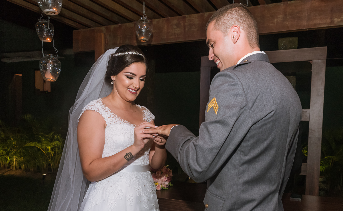 noiva colocando aliança na mão do noivo