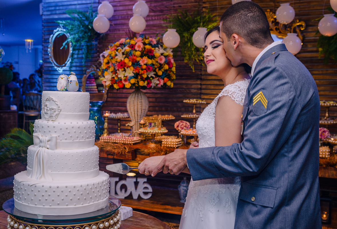 noivos se beijando na mesa do bolo