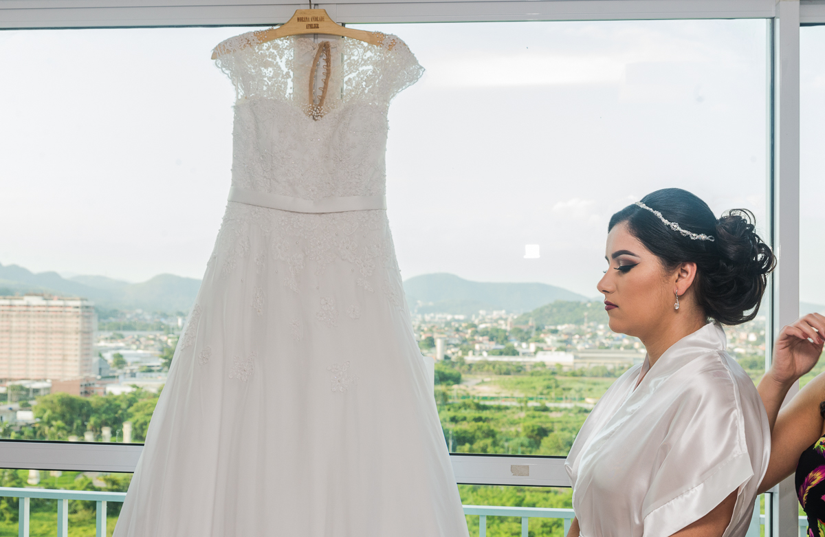 noivas rj, noiva sendo maqueada com o vestido de noiva do atelier morena andrade ao fundo, maquiadora mariana castro dia de noiva por andre nogueira fotografia