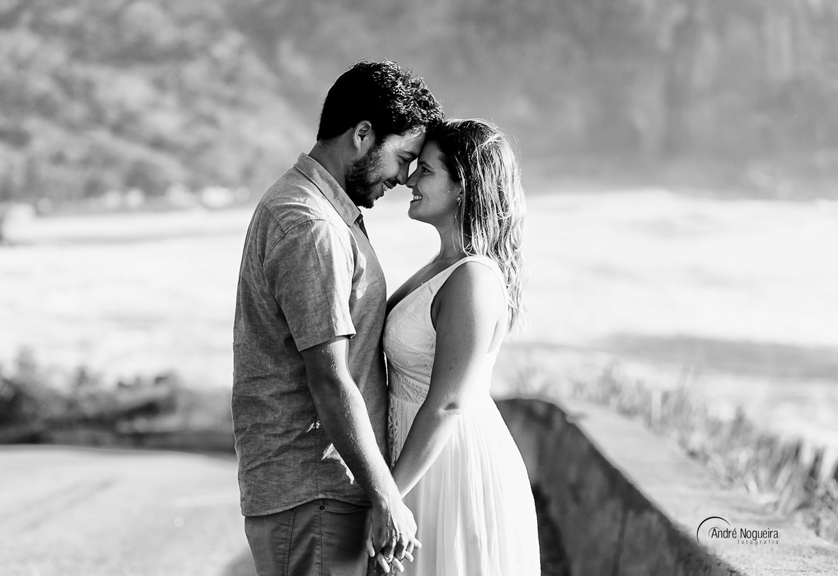 casal de frente um para o outro de cabeça encostada e com o visual lindo da praia da prainha ao fundo