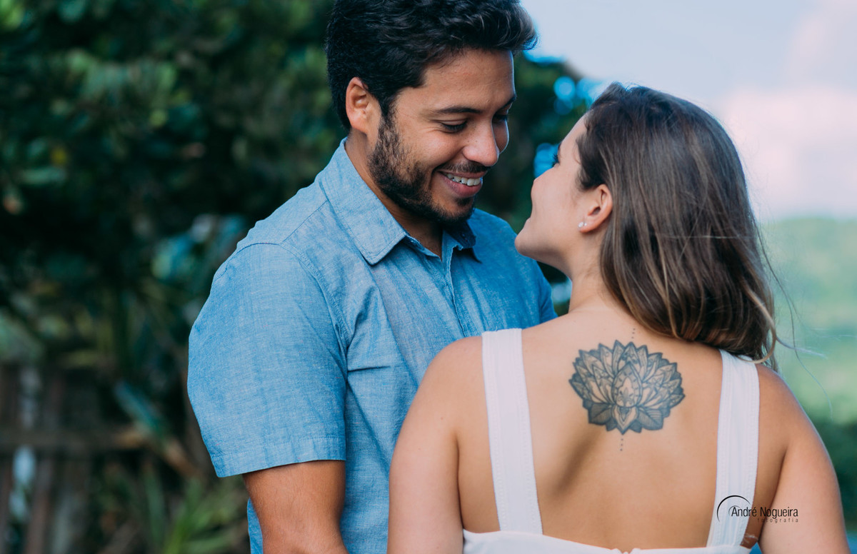 noivo olhando apaixonado para a noiva e a linda tatuagem nas costas da noiaparecendo