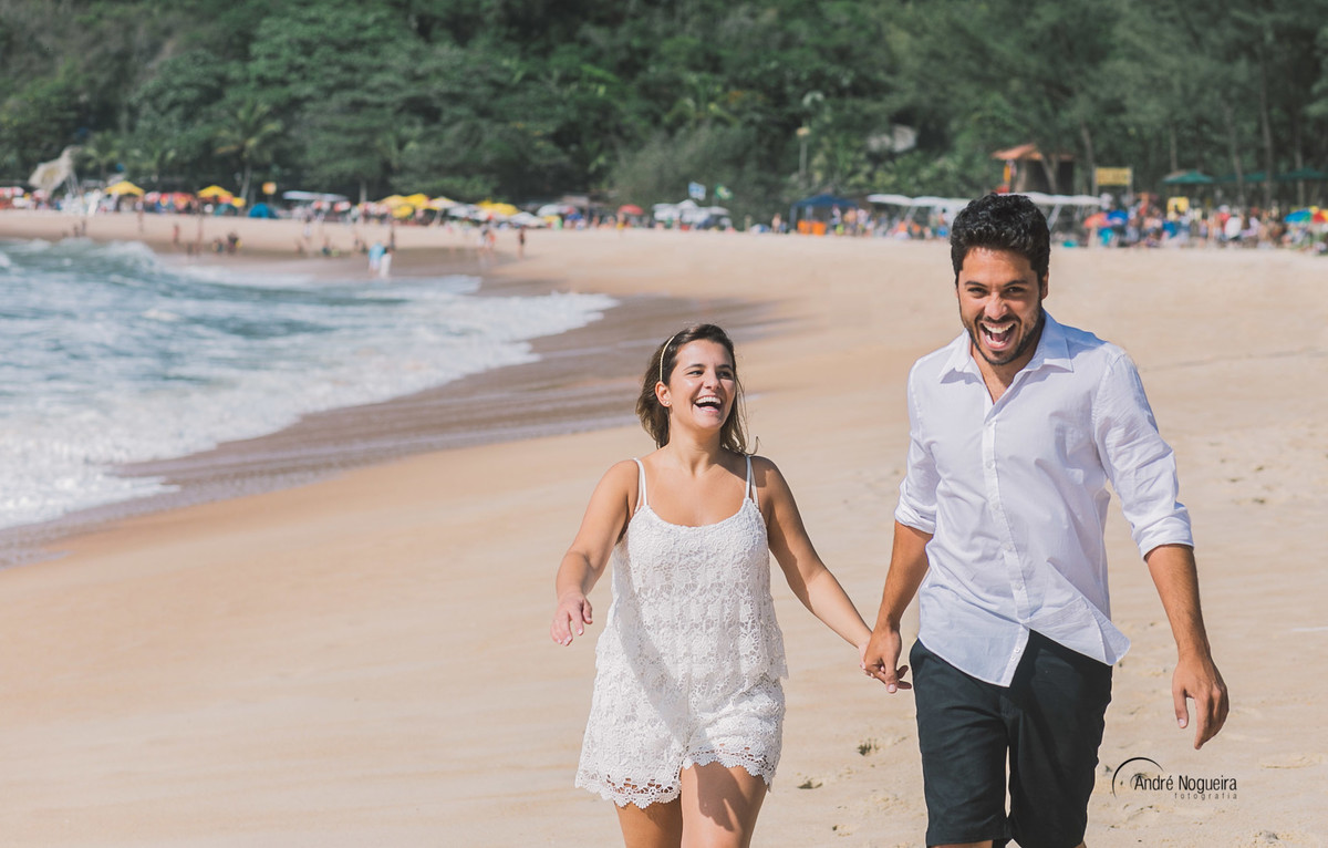 correndo na areia da praia de uma forma animada, os noivos sorriem e brincam um com o outro