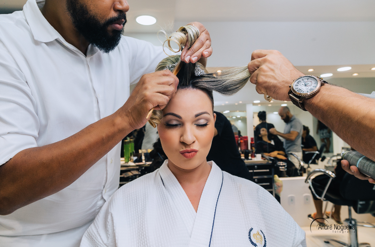noiva tendo o cabelo arrumado pelo cabelereiro e fazendo careta para o fottógrafo andre nogueira fotografia