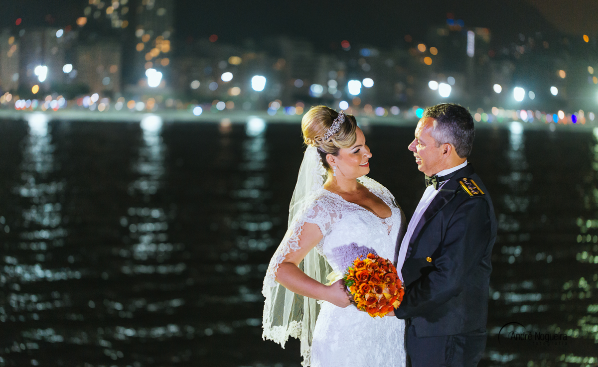 segurando o bouquet de flores, os noivos se olham sorridentes