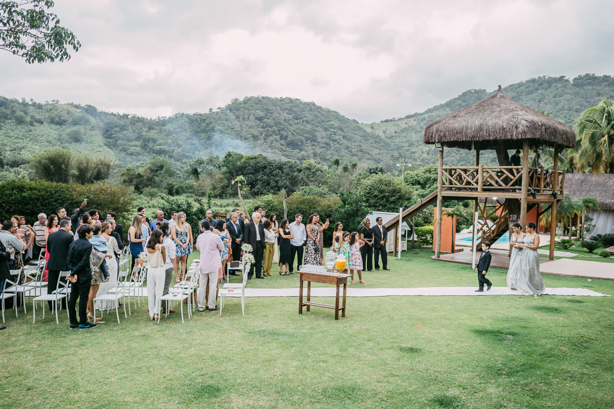 casamento rj,pajens e damas entram pelo corredor da cerimônia de casamento rj, com uma linda paisagem da chácara do sapê ao fundo