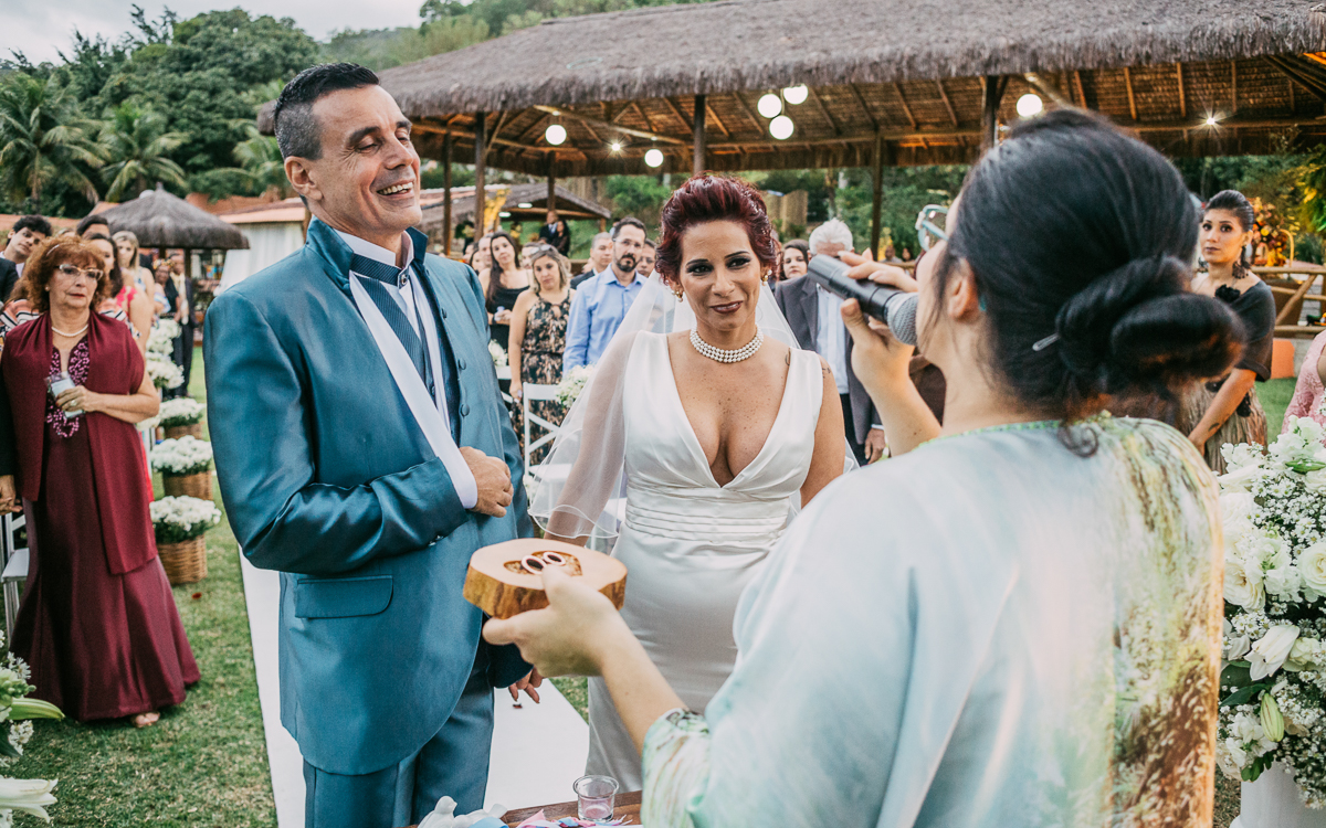fotografia de casamento rj, celebrante segurando as alianças, noivos sorriem pra ela, chácara do sapê, casamento de dia, andré nogueira fotografia