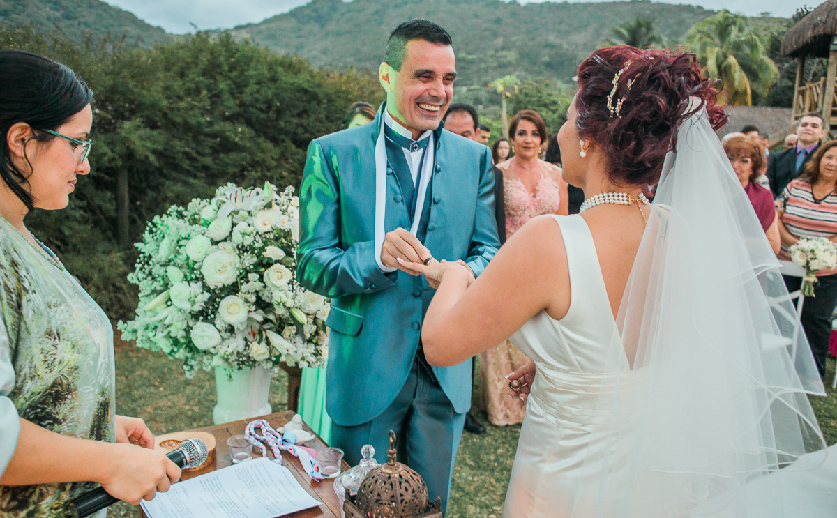 casamento rj, casamento de dia, casamento rj, noivo colocando aliança no dedo da noiva durante a cerimônia de casamento no sítio chácara do sapê, foto por andré nogueira fotografia