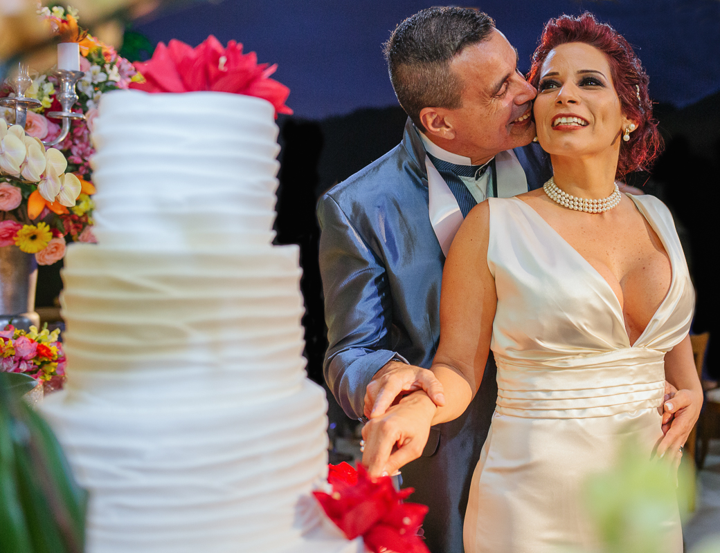 casamento rj, noivos posando cortando o bolo, noivo beija o rosto da noiva, fotografado por andre nogueira fotografia, chácara do sapê