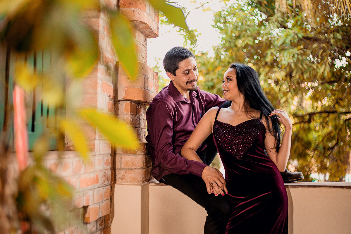 foto da noiva olhando para o noivo sentado em uma mureta perto da rua do porto em piracicaba