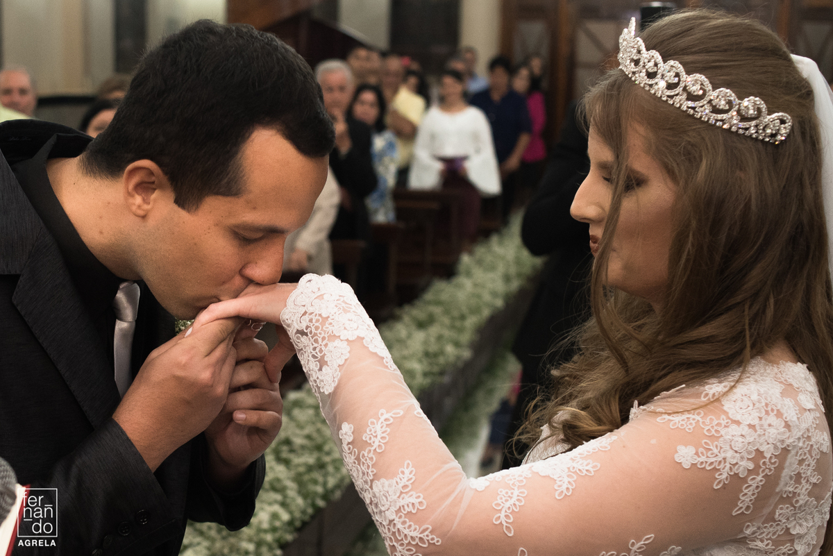 noivo beijando a mão da noiva com aliança de casamento