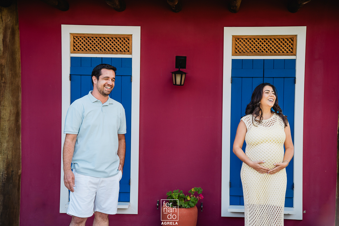 casal com mulher gestante em frente a duas janelas