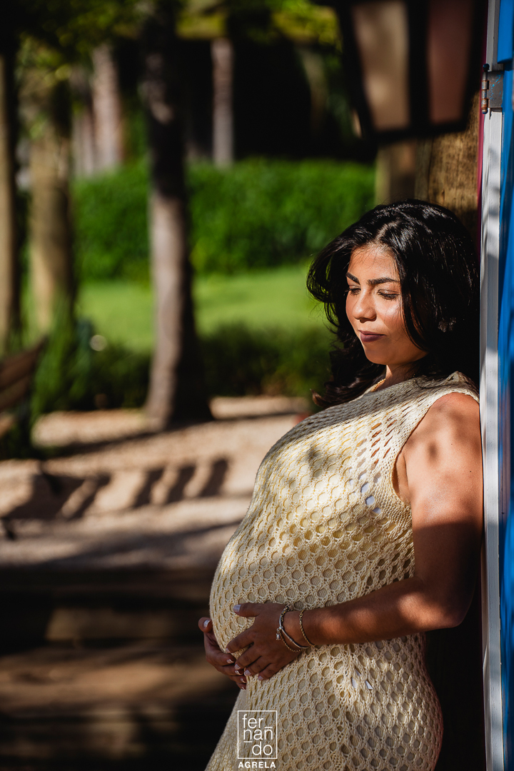 fotografia de mulher gestante em uma area de smbras mbaixo de um deck