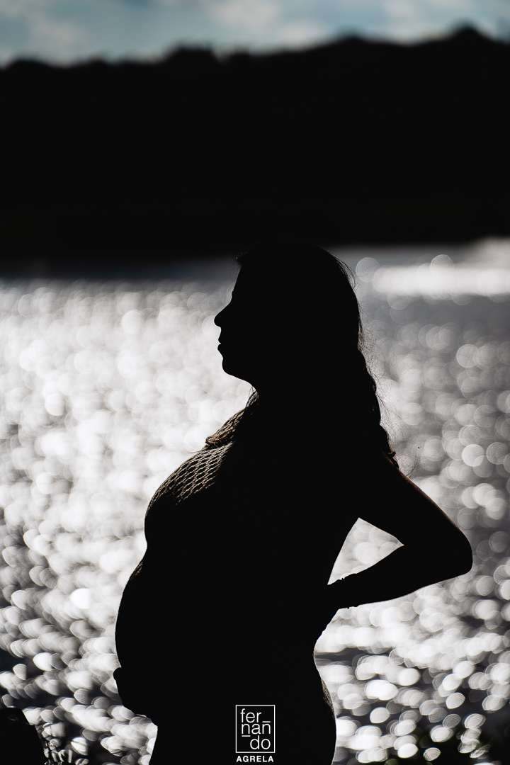 silhueta de mulher gestante com um lago ao fundo