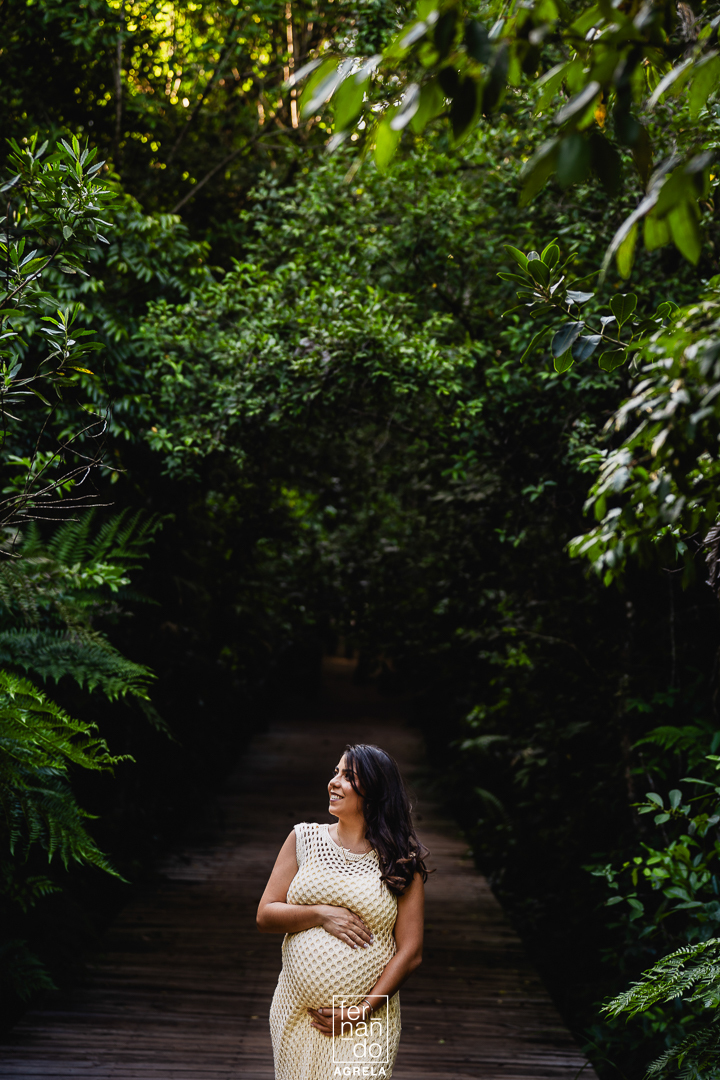 fotografia de mulher gravida com arvores em volta em ima de um deck