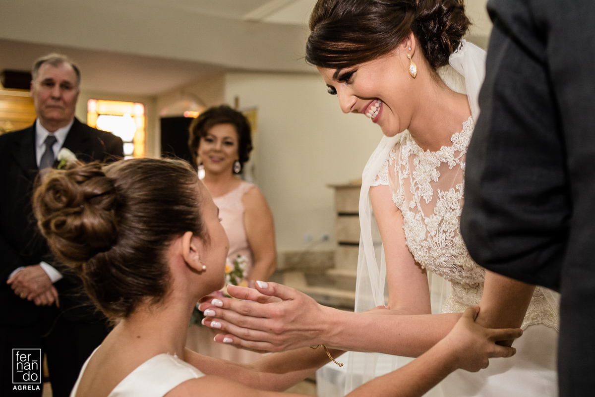 noiva sorrindo para daminha que levou as alianças