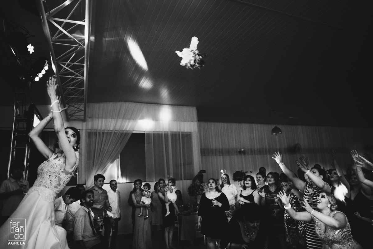 bouquet voando no ar e convidadas pulando para pegar