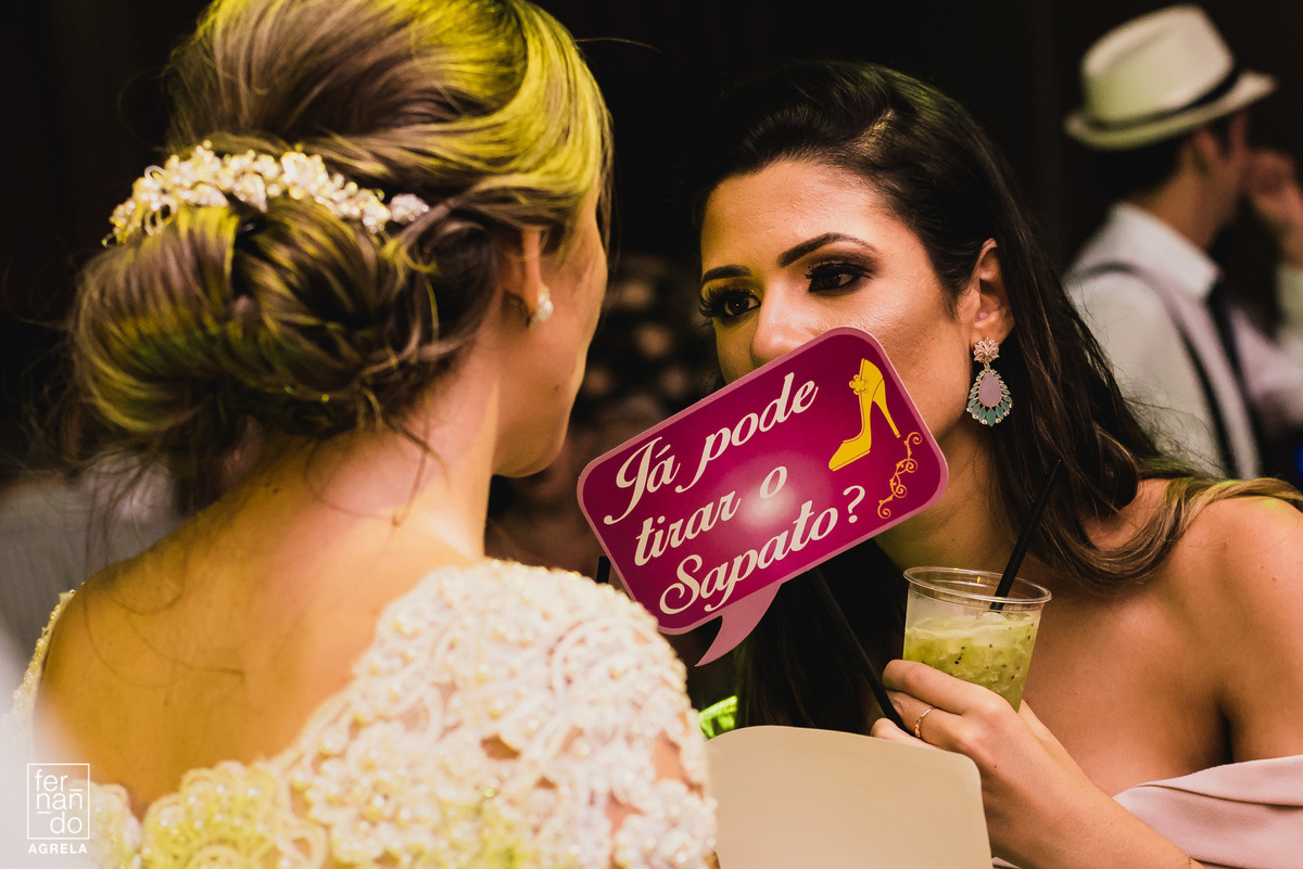 amiga da noiva segurando a plaquinha com a pergunta se pode tirar o sapato quando a pista de dança abriu no casamento