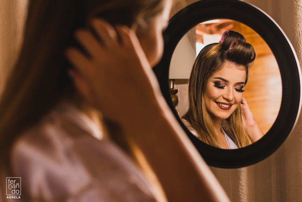 noiva em espelho mostrando detalhes da maquiagem 