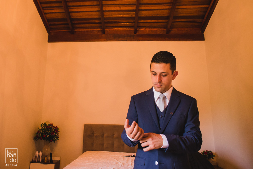 noivo acertando detalhe do terno antes do casamento