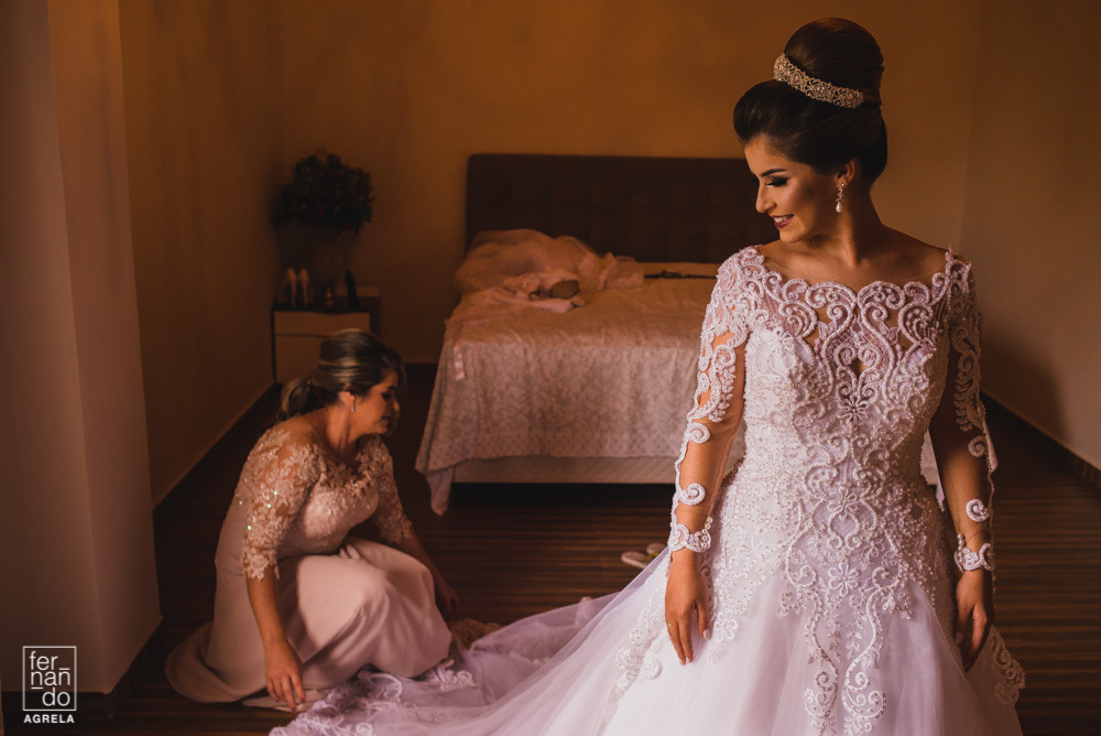 mãe da noiva ajudando a filha a vestir o vestido de noiva