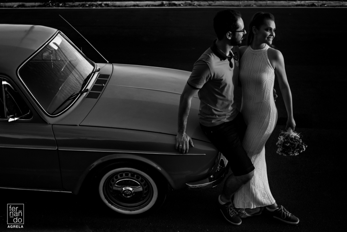 casal iluminados pelo por do sol apoiados em uma caravan