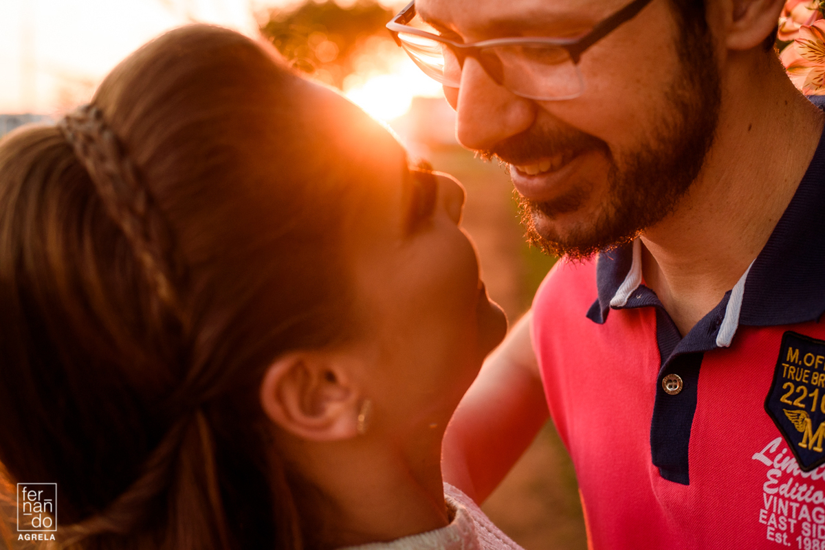 casal sorrindo olhando um para o outro com o por do sol ao fundo
