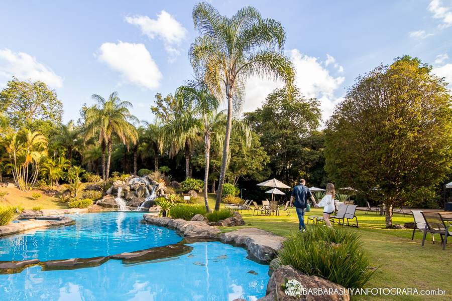 Noivo e noiva caminhando ao lado da piscina natural com lindo c&eacute;u azul no click da fot&oacute;grafa de casamento Minas Gerais MG B&aacute;rbara Suyan no Hotel Ville Real em Ouro Preto com muito amor