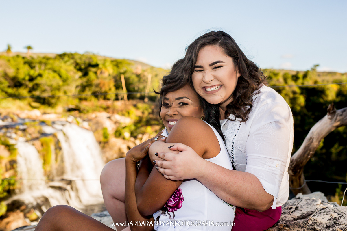 CASAL SORRINDO ABRAÇADO COM CACHOEIRA GRANDE AO FUNDO NA SERRA DO CIPO, MINAS GERIAS, ENSAIO HOMOAFETIVO
