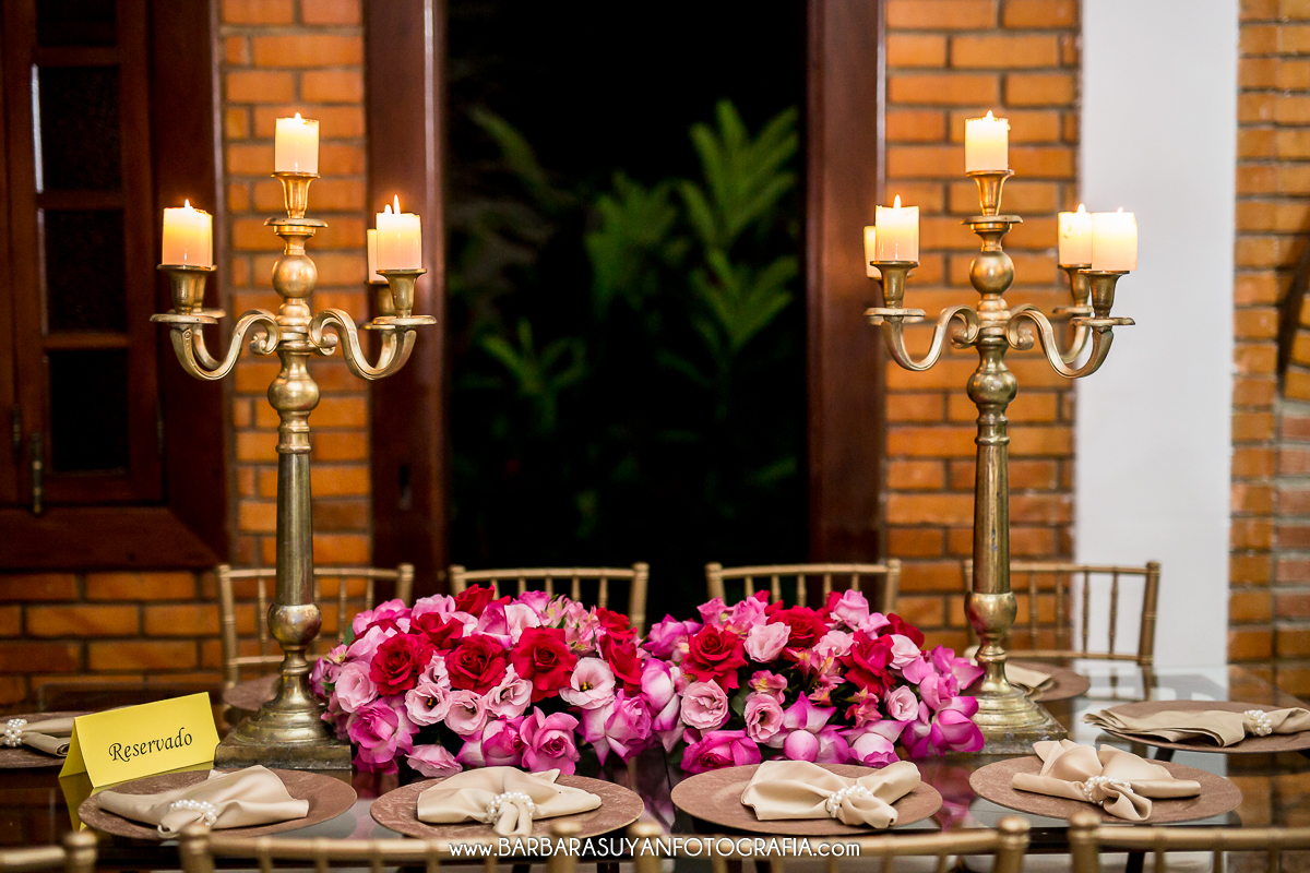 Mesa dos pais com castiçais dourados e guardanapos bege com pérolas. Decoração da recepção de casamento de Lívia e Thiago no Chalé Pampulha. Decoração com rosas e flores naturais, cadeiras douradas e toalhas brancas