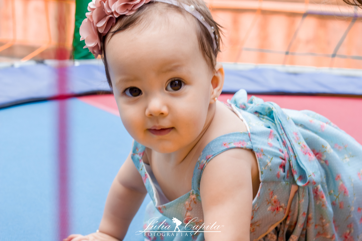 Bebê olha para a fotógrafa Júlia Capita enquanto brinca na cama elástica
