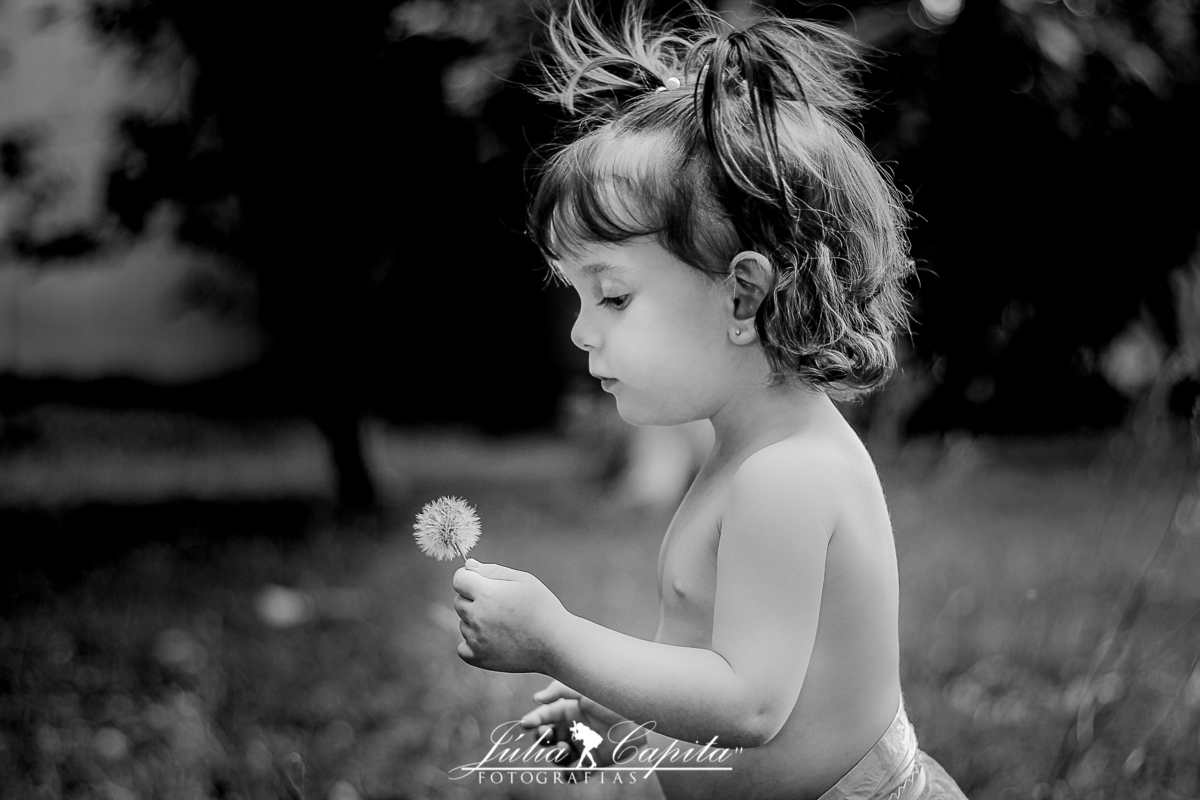 Criança assoprando dente de leão no Parque Municipal
