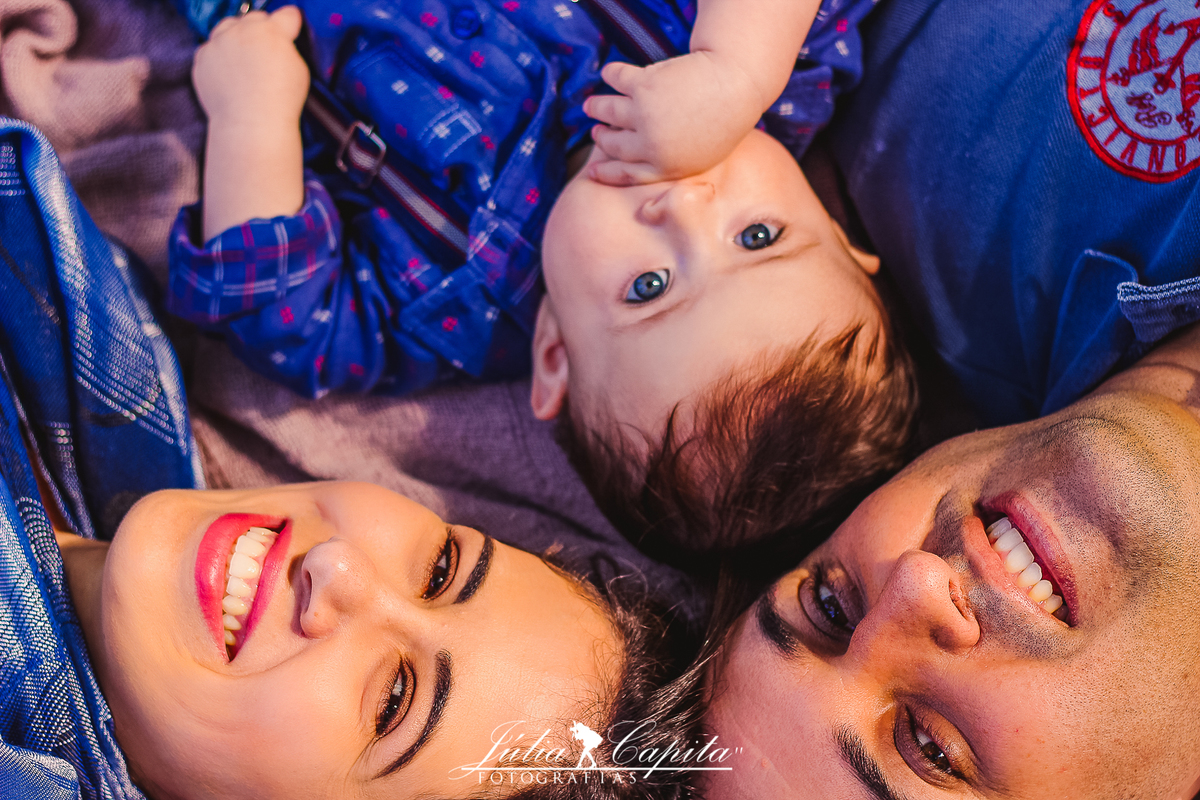 Família deitada na grama em ensaio fotográfico por Júlia Capita
