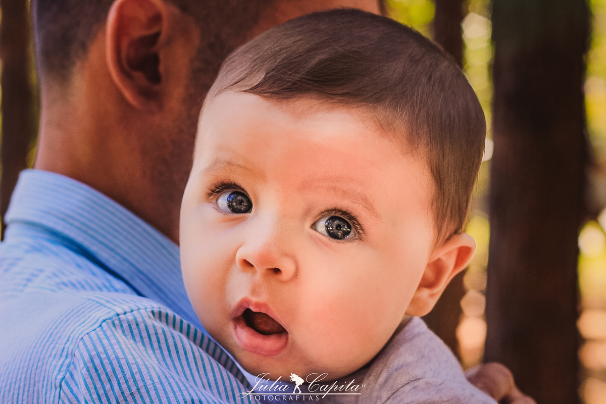 Pai segurando o seu bebê no colo em ensaio fotográfico por Júlia Capita