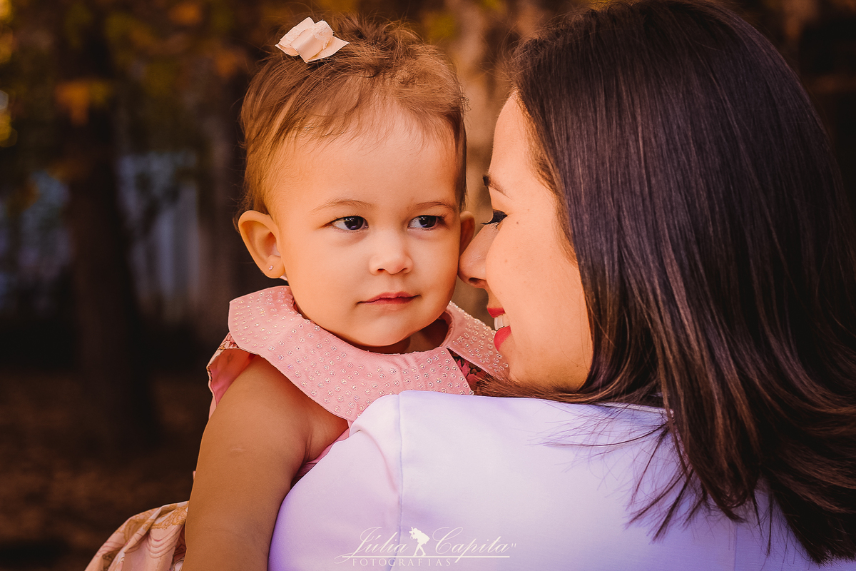 Mãe abraçando a filha com amor durante ensaio fotográfico