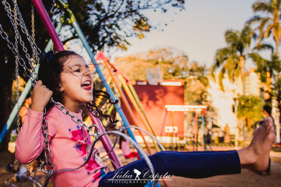 Menina se divertindo no balanço do Parque Infantil em ensaio fotográfico